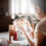 selective focus photography of woman feeding baby